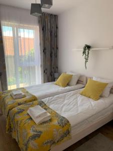2 łóżka w sypialni z żółtymi poduszkami w obiekcie Apartament Joanna w mieście Giżycko