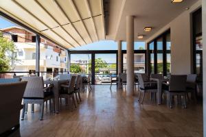 a dining room with tables and chairs and windows at Hotel Hills Ulcinj in Ulcinj