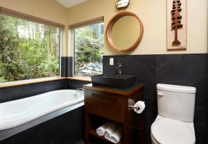 a bathroom with a tub and a toilet and a sink at Middle Beach Lodge in Tofino