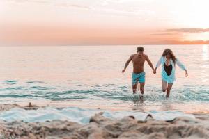 a man and a woman walking in the water on the beach at Marina di Scarlino Resort in Puntone di Scarlino