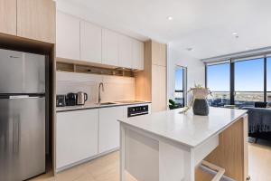 a kitchen with white cabinets and a white counter top at Chic 1-Bed with City Views, Parking, Gym & Pool in Melbourne