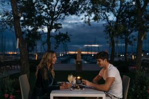 a man and a woman sitting at a table with a candle at Marina di Scarlino Resort in Puntone di Scarlino
