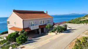 a house on a hill next to the ocean at Apartments Tanja in Zavalatica