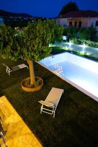 a swimming pool with a chair and a tree at Charikleia's 1st floor appartment in Pelion in Volos