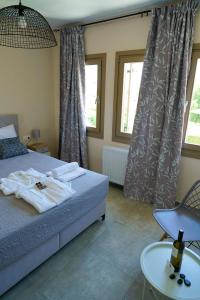 a bedroom with a bed and a table and two windows at Charikleia's 1st floor appartment in Pelion in Volos