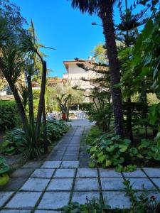 a sidewalk in a park with palm trees and a building at Hotel La Terrazza in Porto San Giorgio