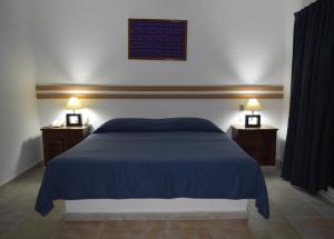 a bedroom with a blue bed and two night stands at Hotel Plaza Almendros in Isla Mujeres