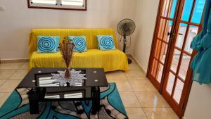 a living room with a yellow couch and a table at Gorizia in Sainte-Anne