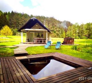 a backyard with a pool with two chairs and a house at White homestead in Sumiliszki