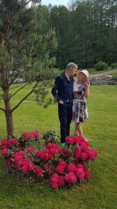 un hombre y una mujer de pie junto a un montón de flores en White homestead, en Semeliškės