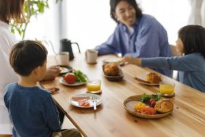 una familia sentada en una mesa comiendo comida en THREE - Vacation STAY 38687v, en Tokio