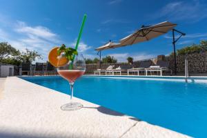 a drink in a glass next to a swimming pool at Villa Parisa in Božava