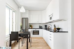 a white kitchen with a black table and chairs at 2ndhomes Tampere "Kanava" Apartment - 54m2 Apt with Private SAUNA & Balcony - 11th floor in Tampere