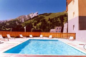 a large swimming pool with chairs and a building at La Foux d'Allos in La Foux