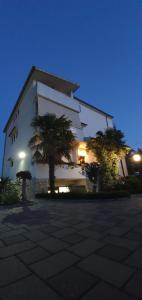 a large white building with palm trees in front of it at Apartments Sime in Sukošan