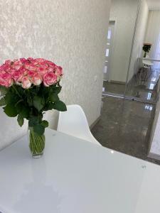 um vaso de rosas cor-de-rosa sentado numa mesa em Люкс Апартаменты в центре города ,ЖК Театральный em Rivne
