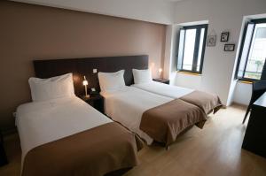 um quarto de hotel com duas camas e duas janelas em Hotel Vitória em Coimbra