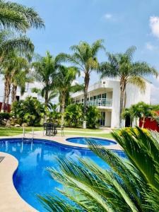 uma piscina com palmeiras em frente a um edifício em Hotel Cascada em Cuautla Morelos