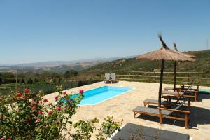 a swimming pool with a straw umbrella and two chairs and a bench at The Wild Olive Andalucía Agave Guestroom in Casares