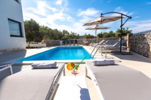 uma piscina com uma mesa e um guarda-sol em Luxury Apartments Mauro with Heated Pool em Božava