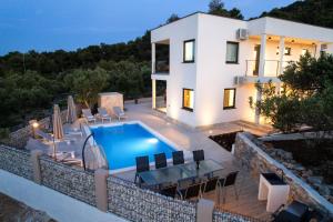 a villa with a swimming pool in front of a house at Luxury Apartments Mauro with Heated Pool in Božava