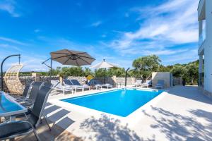 una piscina con sillas y sombrilla en Luxury Apartments Mauro with Heated Pool en Božava