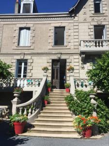 a house with stairs and potted plants in front of it at Lime trees in Arnac-Pompadour