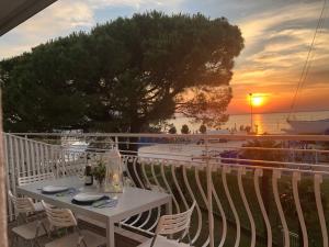 Biały stół i krzesła na balkonie z widokiem na zachód słońca w obiekcie Marine House w Lignano Sabbiadoro