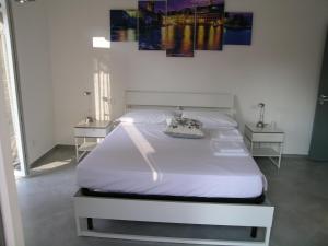 ein weißes Bett in einem Schlafzimmer mit 2 Tischen in der Unterkunft lamarmora9 in La Spezia