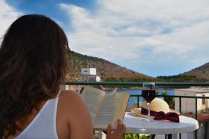 a woman reading a book with a glass of wine at Bob's Apartments in Tolo