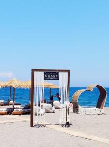 een bord op een strand met stoelen en parasols bij The Coast in Anaxos