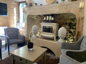 a living room with a fireplace and two chairs and a table at Le Noyer Résidence B&B in Le Bugue