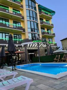 un hotel con piscina di fronte a un edificio di Hotel Condori a Kobuleti