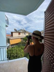 uma mulher a tirar uma foto da vista da sua varanda em Bob's Apartments em Tolo