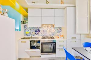 uma cozinha com armários brancos e detalhes azuis em Casa di Linda em Maiori