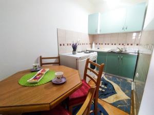 a kitchen with a wooden table with a plate of food on it at Apartman kod autobuske in Bijeljina