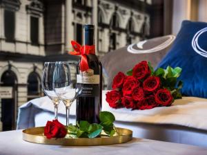 a bottle of wine and a glass on a table with roses at Hotel Logos Kraków in Krakow