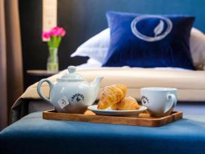 a tray with a teapot and a plate of pastries and a cup at Hotel Logos Kraków in Krakow