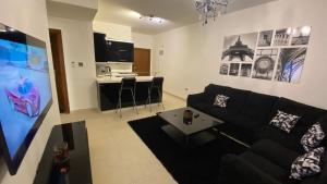 a living room with a black couch and a kitchen at Dair Ghbar Apartment in Amman