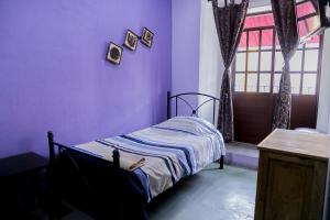 a bedroom with a bed with purple walls and a window at Hotel el Descanso in Puebla