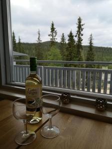 a bottle of wine and two glasses on a table with a window at Ruka - Vuosselin Helmi B21 in Ruka