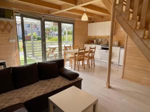 a living room and kitchen with a couch and a table at Kapitanskie Domki in Trzęsacz