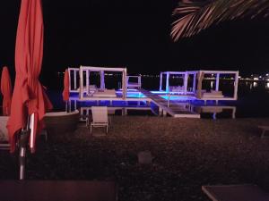 a group of white chairs and a pool at night at Apartments Sime in Sukošan