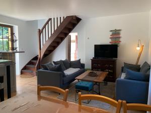 una sala de estar con 2 sofás y una escalera en Gîte - Le Petit Noyer, en Le Bugue