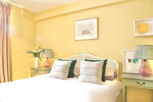 una camera da letto con un letto bianco con due lampade di The Court Yard a Bowness-on-Windermere Altre 3 foto