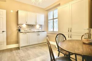 uma cozinha com armários brancos e uma mesa com cadeiras em The Court Yard em Bowness-on-Windermere