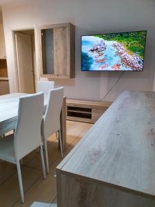 uma sala de estar com uma mesa e uma televisão na parede em AM apartment em Olbia