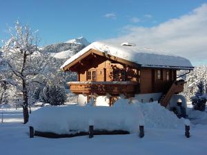 una baita di tronchi ricoperta di neve e dotata di tetto ricoperto di neve di Ferienwohnung Gassoid a Fieberbrunn