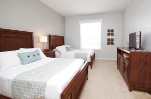 a bedroom with two beds and a flat screen tv at Shoreway Condo #231521 in Orlando