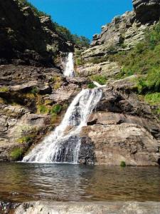 una cascata sul fianco di una montagna accanto a un corpo d'acqua di Casa do Doutor Palheiro a Travassos